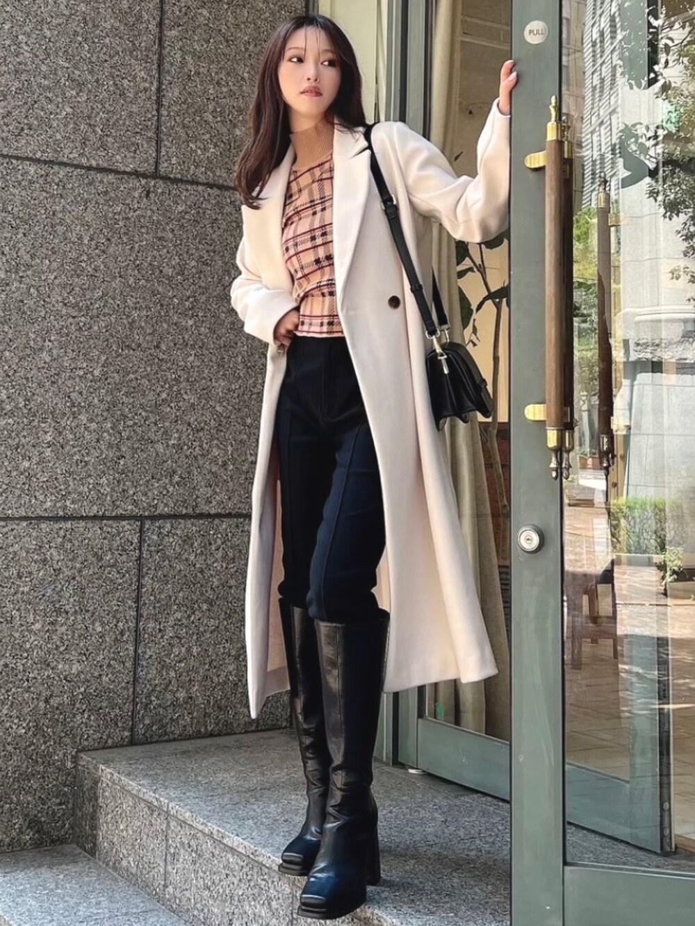 ブラック系のその他パンツ、ブラック系のブーツ、ホワイト系のチェスターコートを着用したレディースの秋コーディネートの3枚目の写真