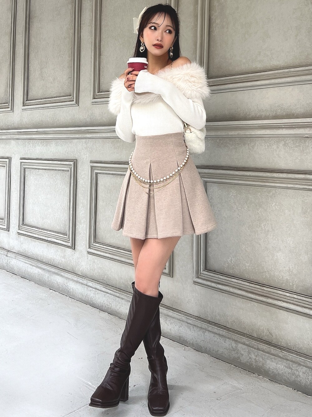 ホワイト系のニット/セーター、ベージュ系のスカート、ホワイト系のハンドバッグを着用したレディースの秋コーディネートの4枚目の写真