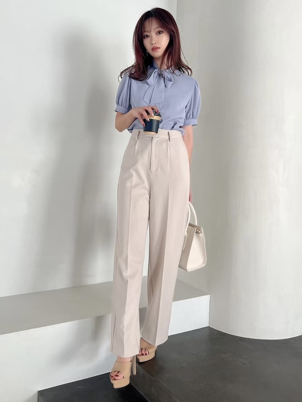 ホワイト系のハンドバッグ、ベージュ系のサンダル、ブルー系のシャツ/ブラウスを着用したレディースの春コーディネートの2枚目の写真