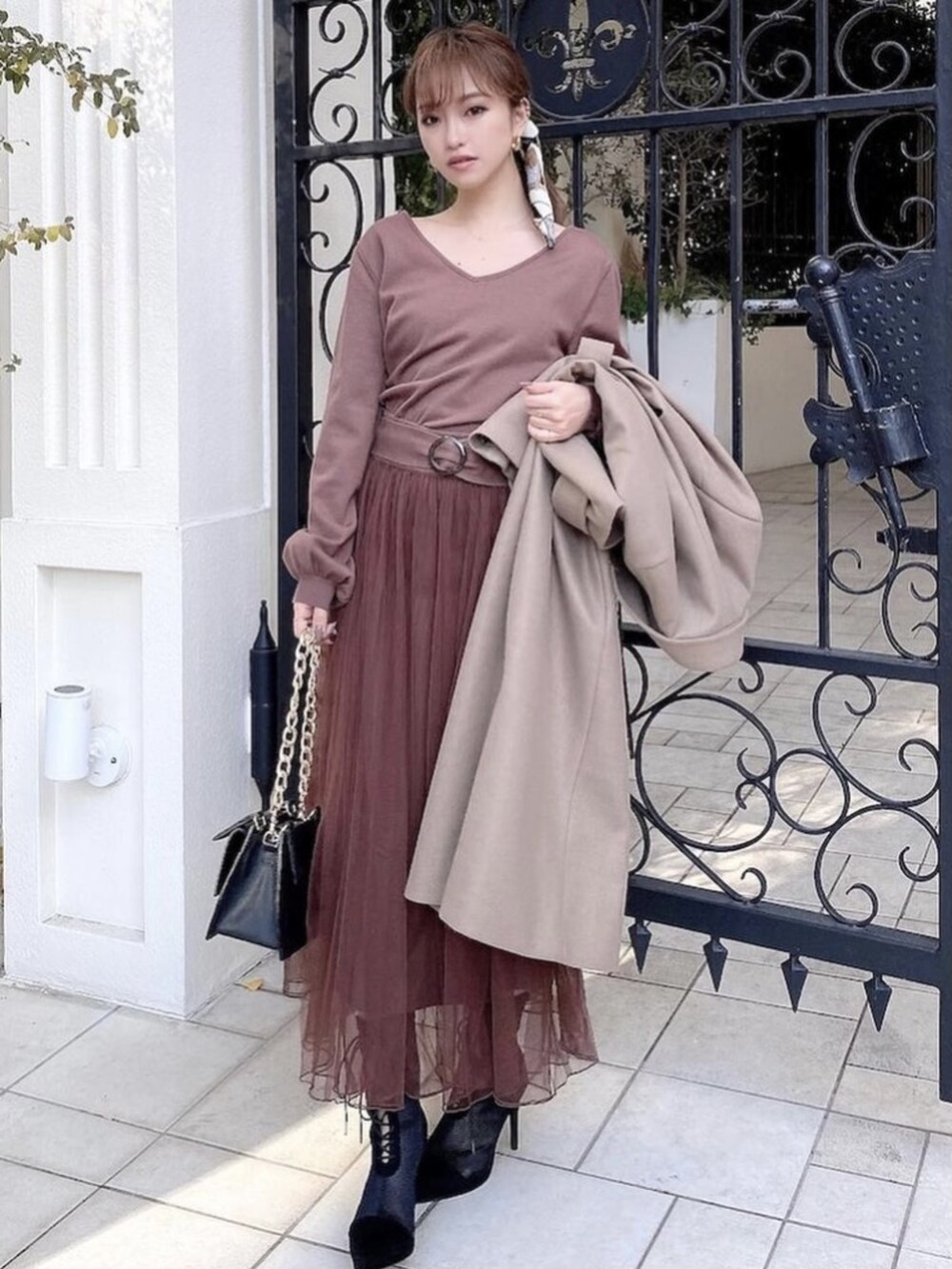 ベージュ系のチェスターコート、ブラウン系のワンピース、ブラック系のブーツを着用したレディースの冬コーディネートの2枚目の写真