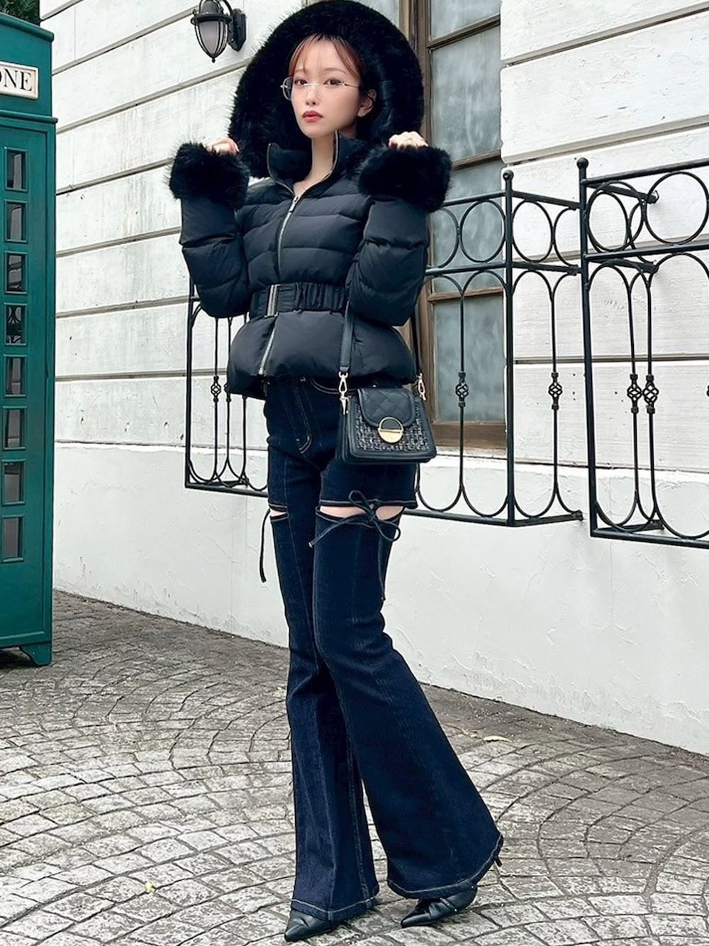 ブラック系のダウンジャケット/コート、ブルー系のデニムパンツ、ブラック系のハンドバッグを着用したレディースの秋コーディネートの5枚目の写真