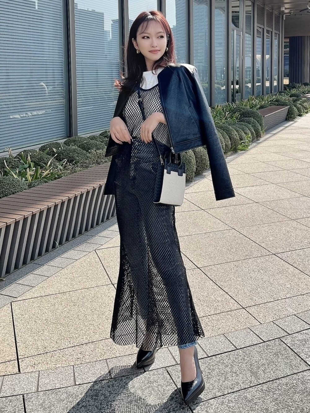 ブラック系のパンプス、ブラック系のノーカラージャケット、ブラック系のワンピースを着用したレディースの春コーディネートの2枚目の写真