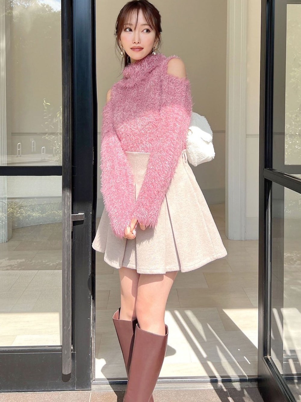 ピンク系のニット/セーター、ホワイト系のハンドバッグを着用したレディースの冬コーディネートの2枚目の写真