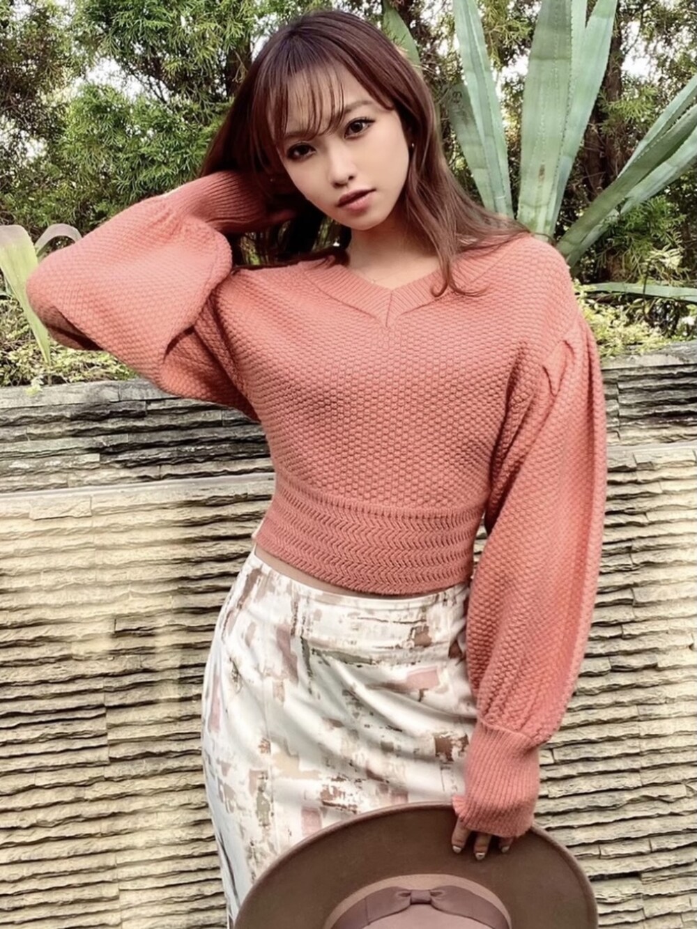 ピンク系のスカート、ホワイト系のパンプス、オレンジ系のニット/セーターを着用したレディースの冬コーディネートの3枚目の写真