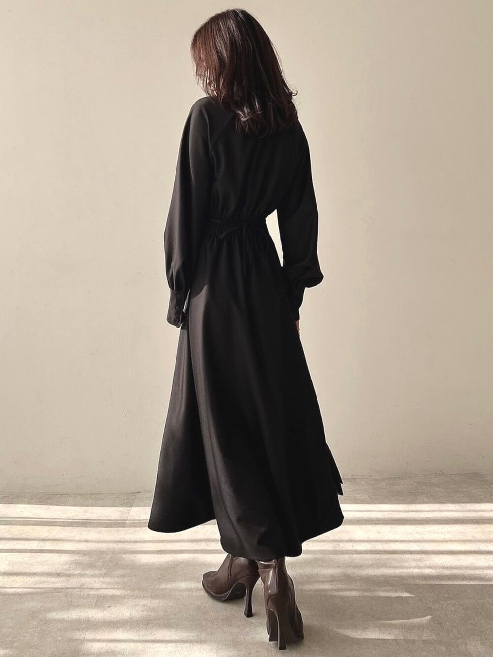 ブラック系のワンピース、ブラウン系のハンドバッグ、ブラウン系のブーツを着用したレディースの冬コーディネートの4枚目の写真