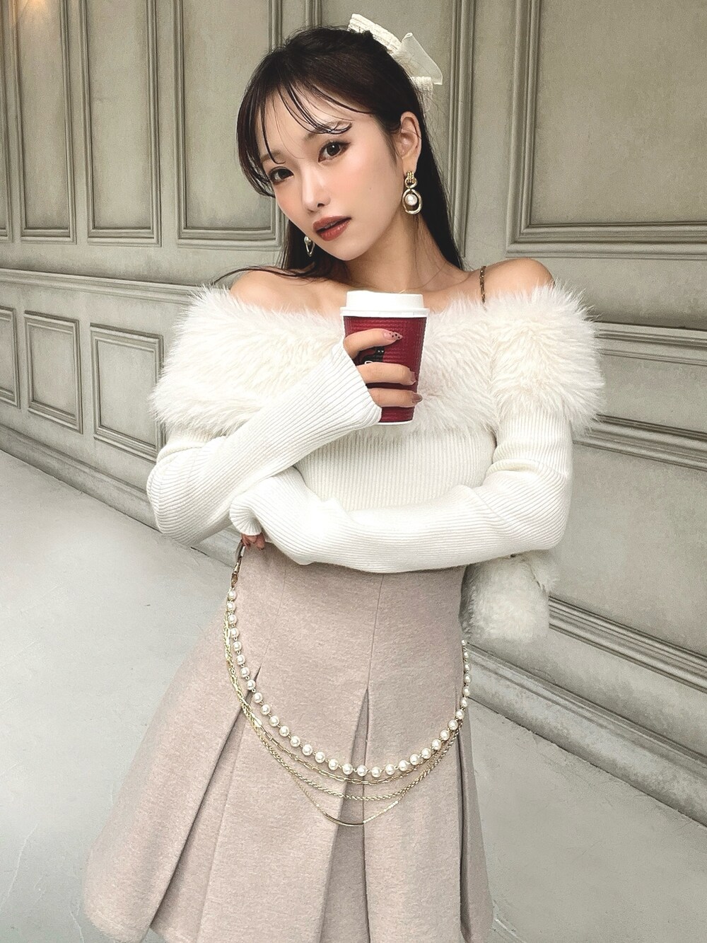 ホワイト系のニット/セーター、ベージュ系のスカート、ホワイト系のハンドバッグを着用したレディースの秋コーディネートの2枚目の写真