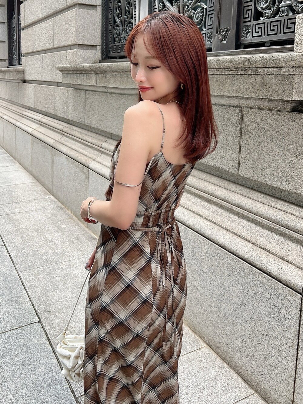 ブラウン系のワンピース、ホワイト系のハンドバッグを着用したレディースの夏コーディネートの3枚目の写真