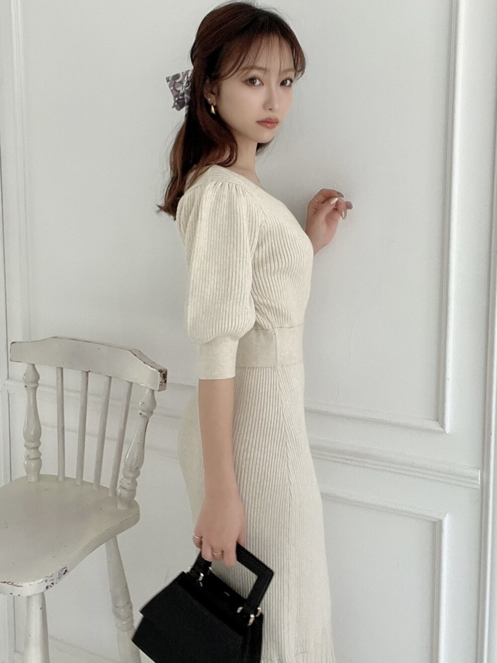 ベージュ系のワンピース、ホワイト系のパンプス、ブラック系のショルダーバッグを着用したレディースの春コーディネートの3枚目の写真