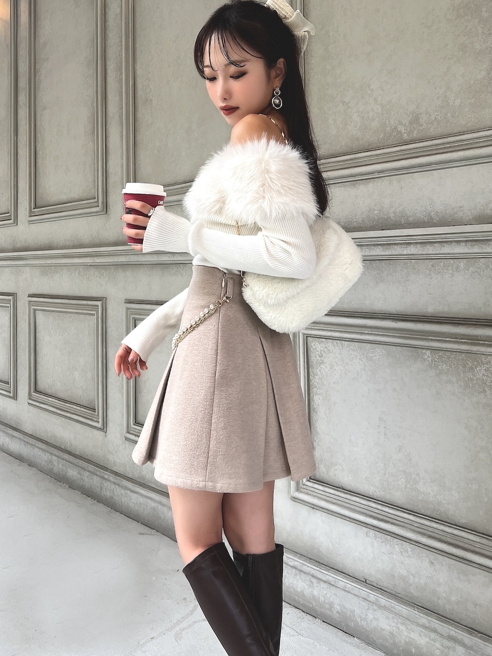 ホワイト系のニット/セーター、ベージュ系のスカート、ホワイト系のハンドバッグを着用したレディースの秋コーディネートの3枚目の写真