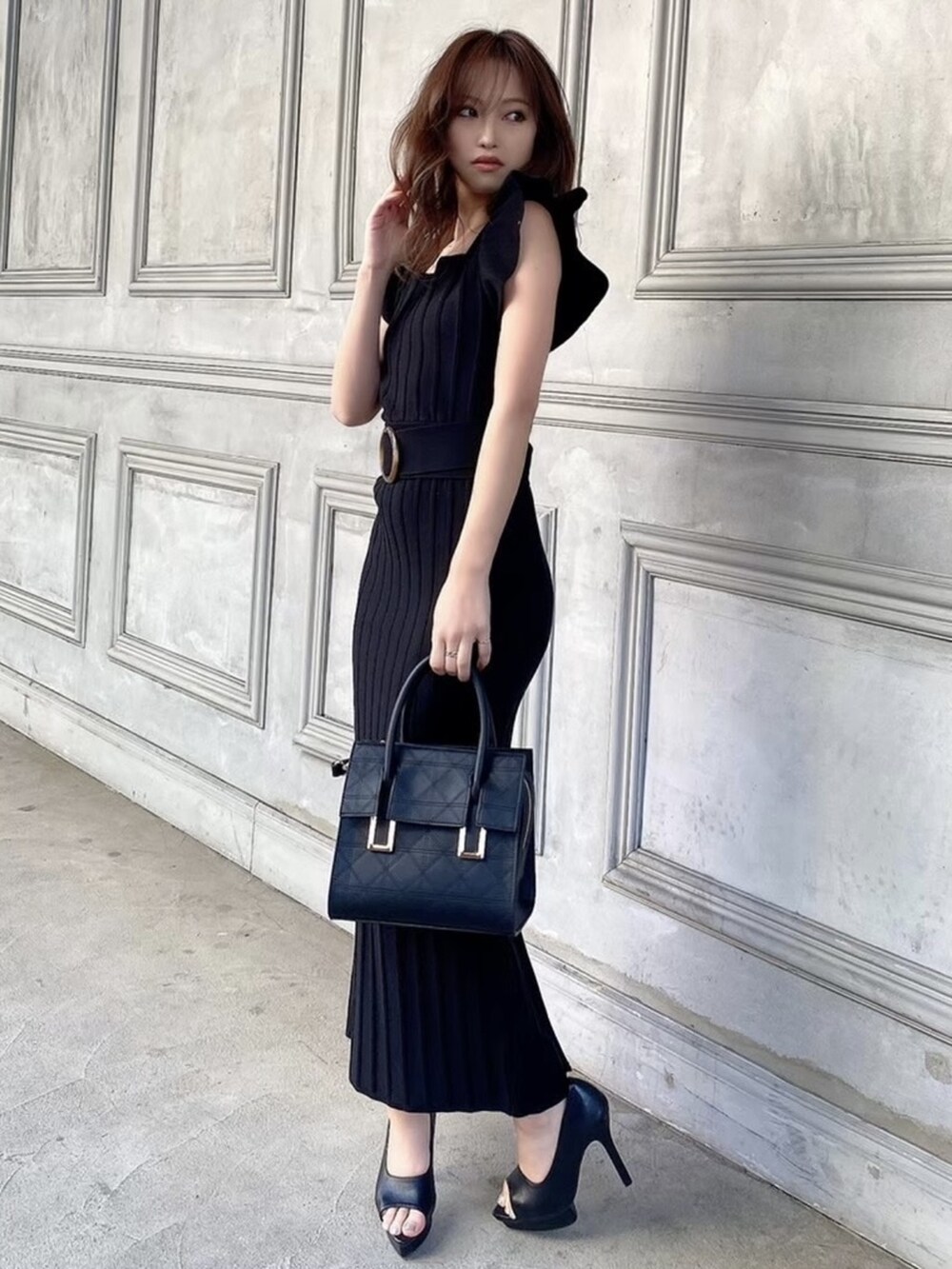 ブラック系のパンプス、ブラック系のワンピース、ブラック系のハンドバッグを着用したレディースの春コーディネートの2枚目の写真