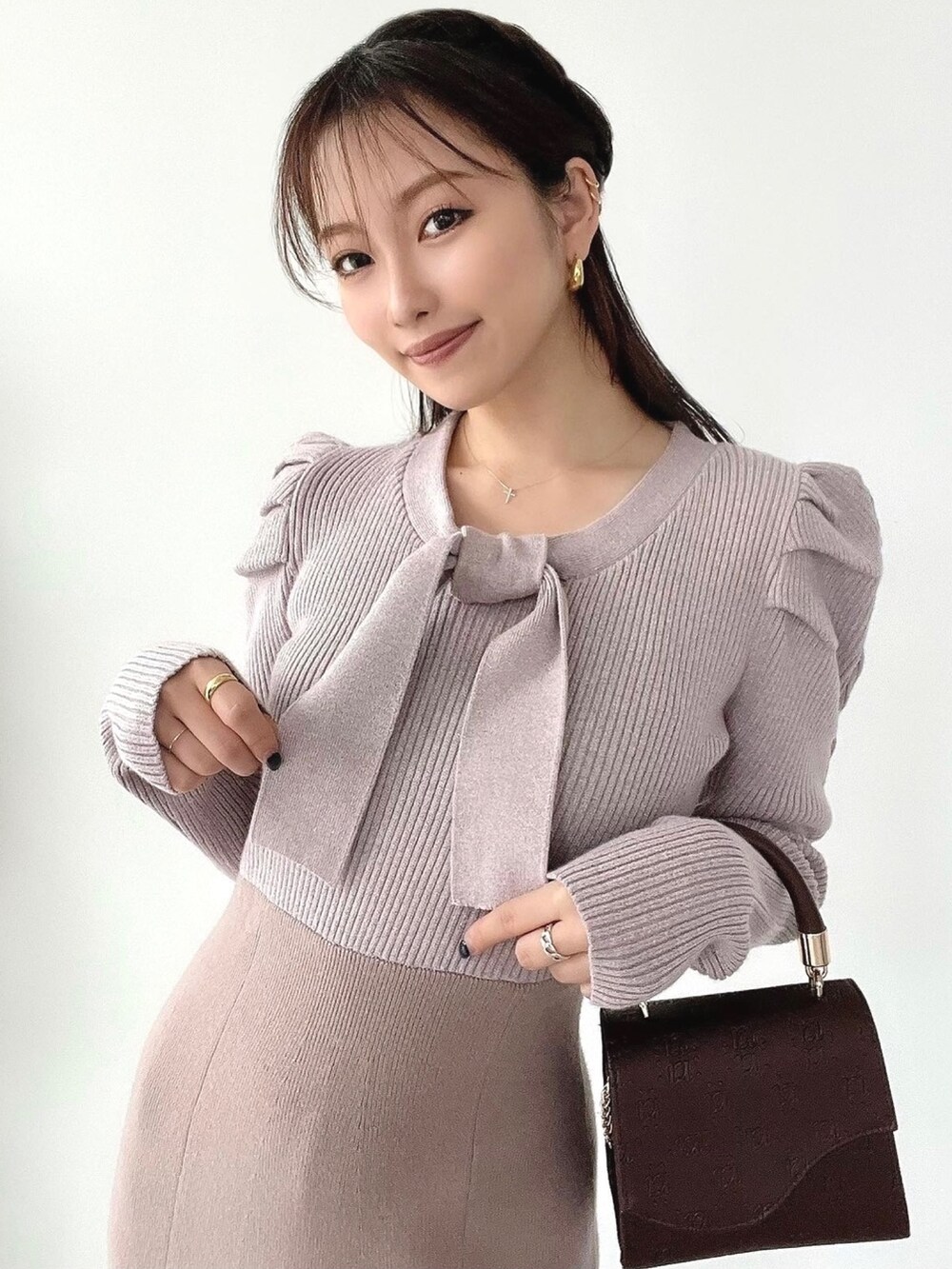 ピンク系のワンピース、ブラウン系のハンドバッグ、ブラウン系のブーツを着用したレディースの冬コーディネートの2枚目の写真