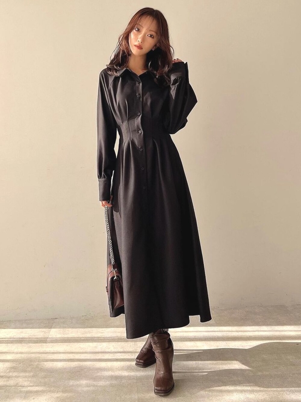 ブラック系のワンピース、ブラウン系のハンドバッグ、ブラウン系のブーツを着用したレディースの冬コーディネートの3枚目の写真