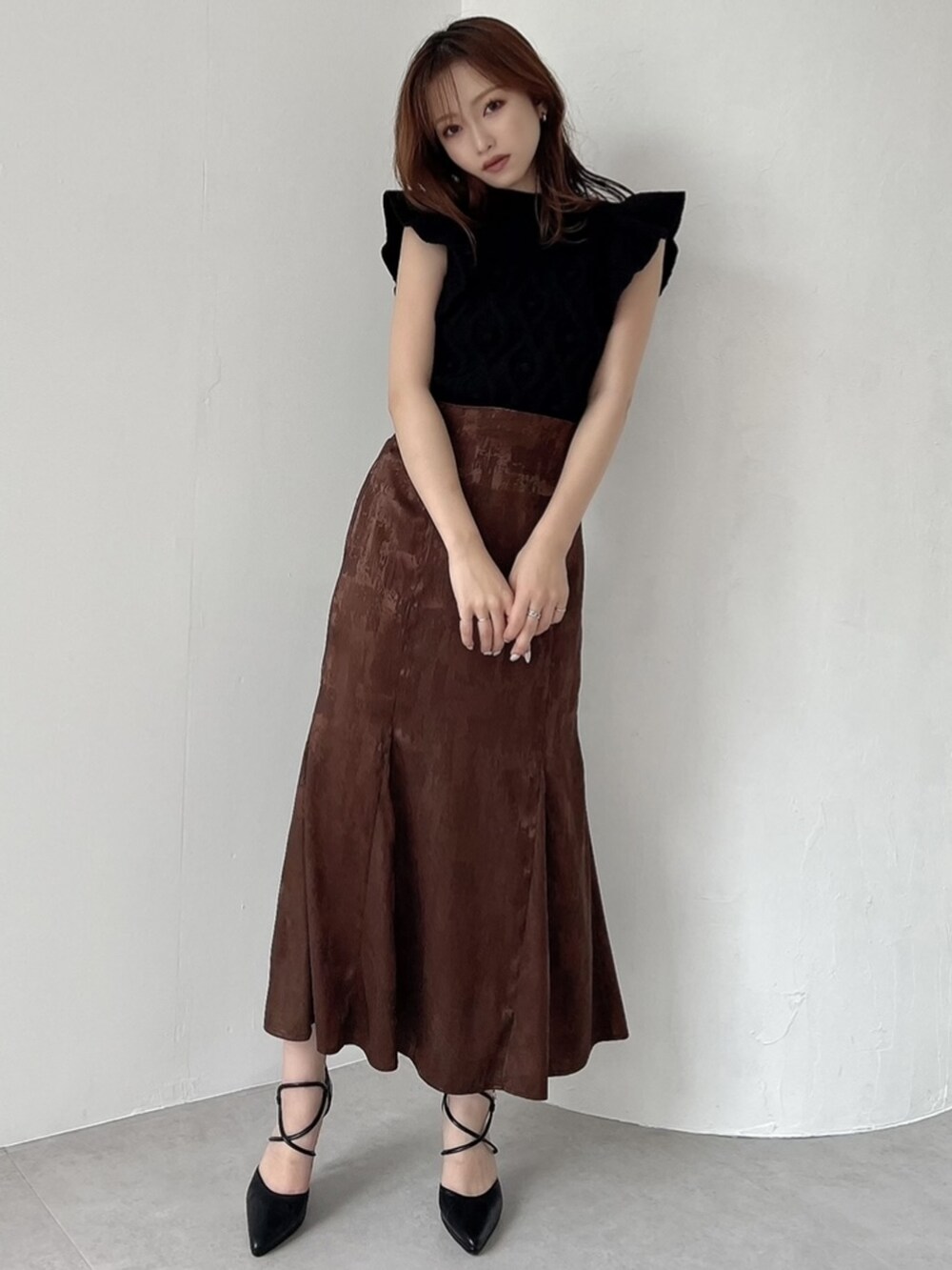 ブラック系のニット/セーター、ブラウン系のスカート、ブラック系のパンプスを着用したレディースの夏コーディネートの3枚目の写真