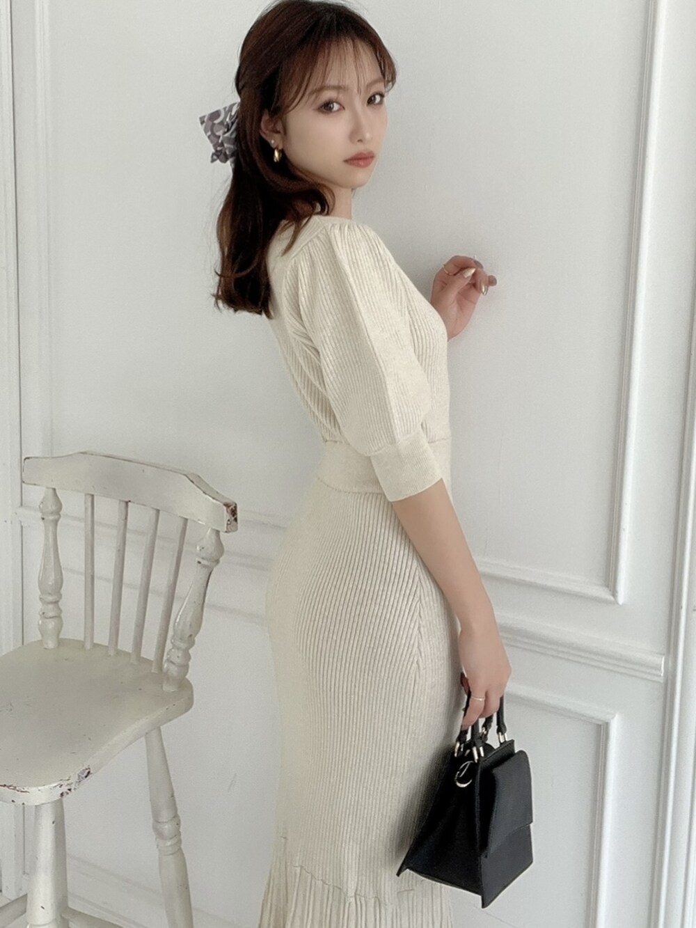 ベージュ系のワンピース、ホワイト系のパンプス、ブラック系のショルダーバッグを着用したレディースの春コーディネートの2枚目の写真