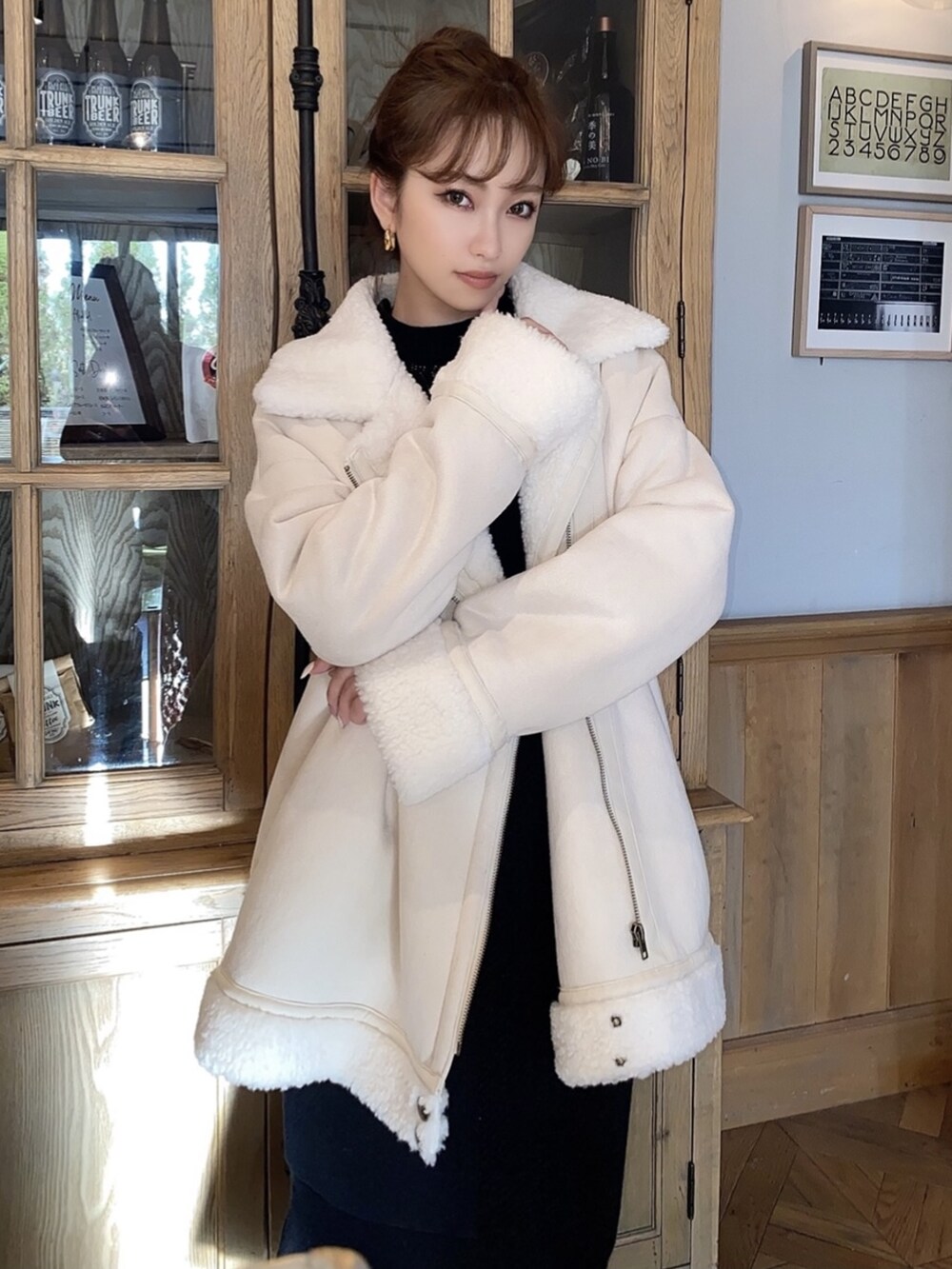 ブラック系のスカート、ブラック系のニット/セーター、ホワイト系のムートンコートを着用したレディースの冬コーディネートの4枚目の写真