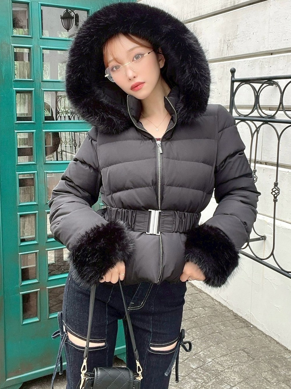 ブラック系のダウンジャケット/コート、ブルー系のデニムパンツ、ブラック系のハンドバッグを着用したレディースの秋コーディネートの3枚目の写真