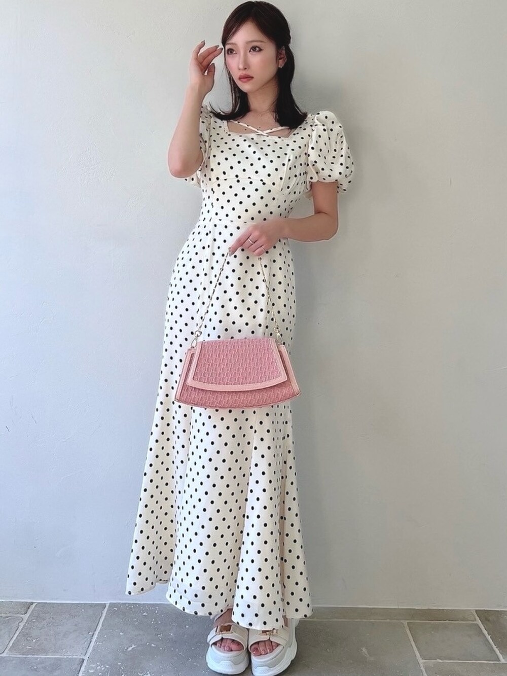 ホワイト系のワンピース、ホワイト系のサンダル、ピンク系のハンドバッグを着用したレディースの春コーディネートの3枚目の写真