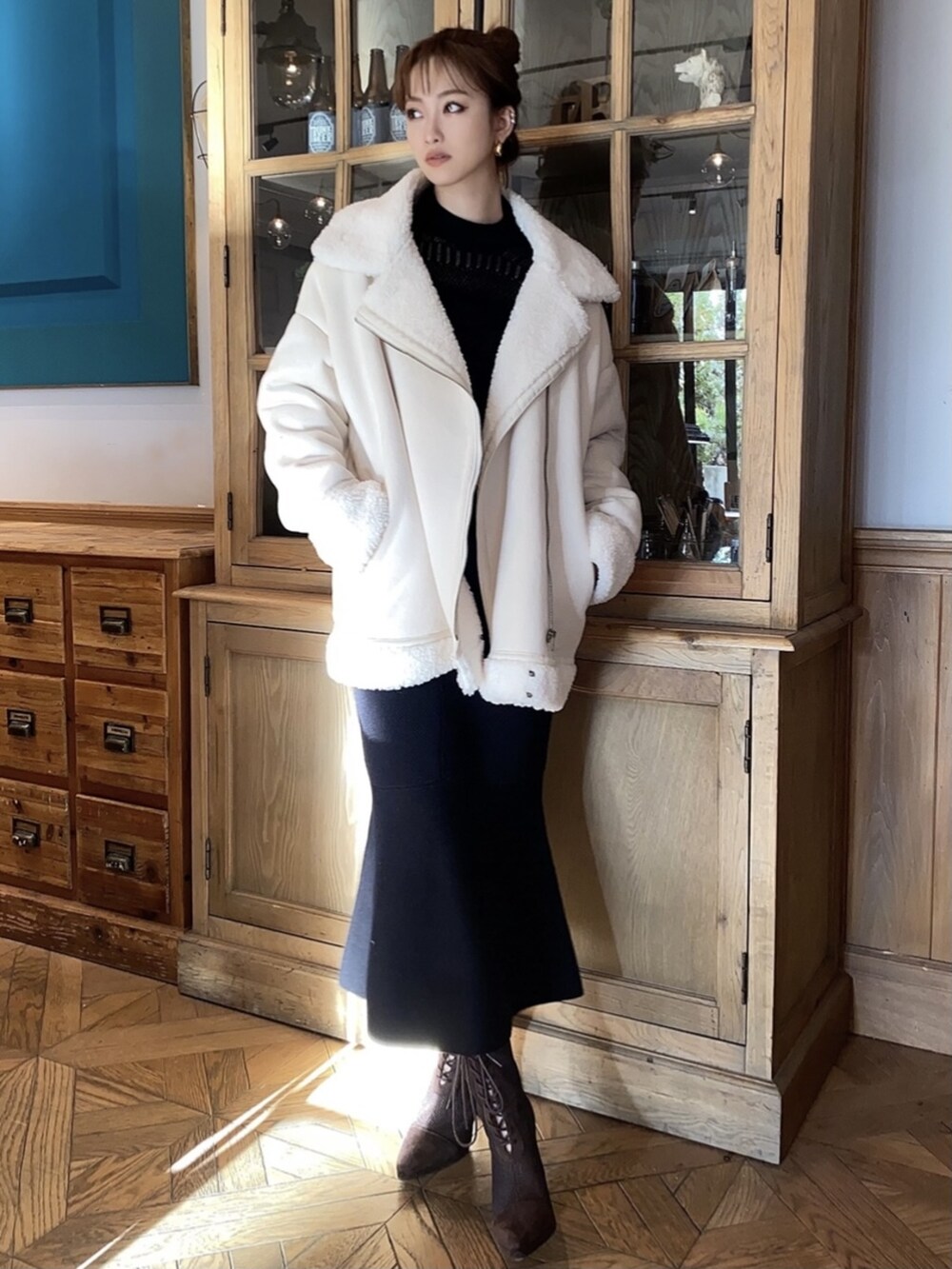ブラック系のスカート、ブラック系のニット/セーター、ホワイト系のムートンコートを着用したレディースの冬コーディネートの2枚目の写真