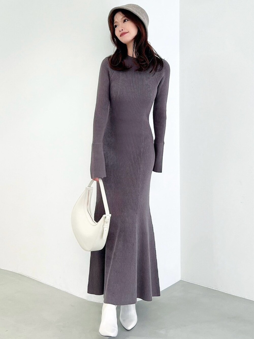 グレー系のワンピース、ホワイト系のブーツ、ホワイト系のハンドバッグを着用したレディースの秋コーディネートの2枚目の写真