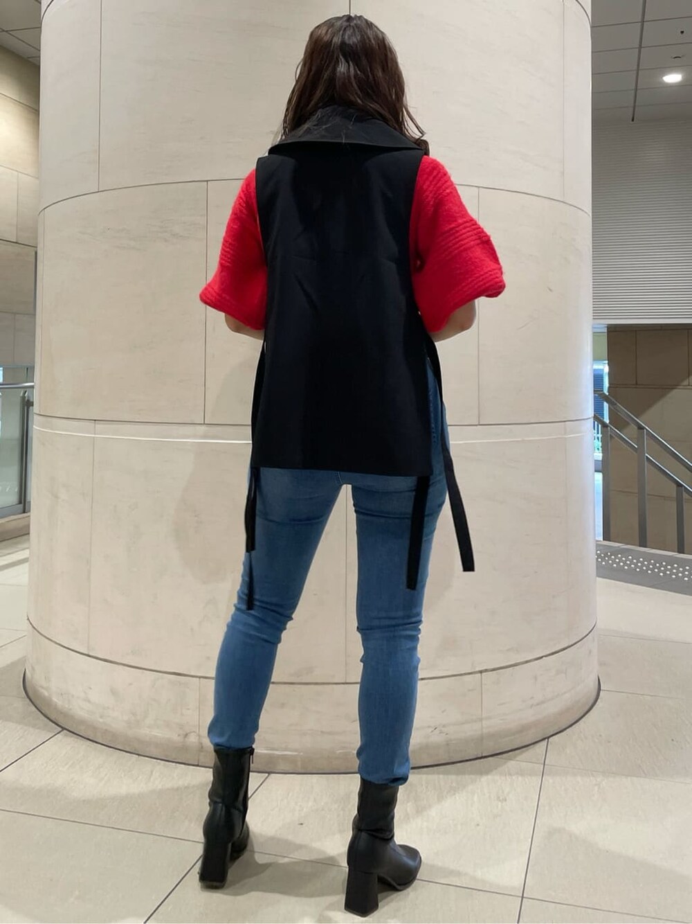 ブラック系のベスト、ブラック系のブーツ、レッド系のニット/セーターを着用したレディースの秋コーディネートの3枚目の写真