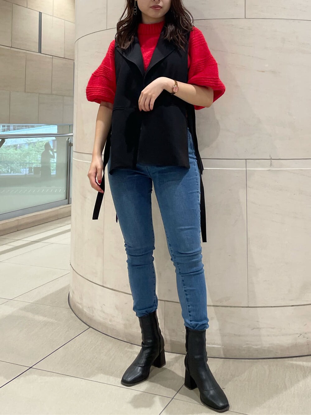 ブラック系のベスト、ブラック系のブーツ、レッド系のニット/セーターを着用したレディースの秋コーディネートの2枚目の写真