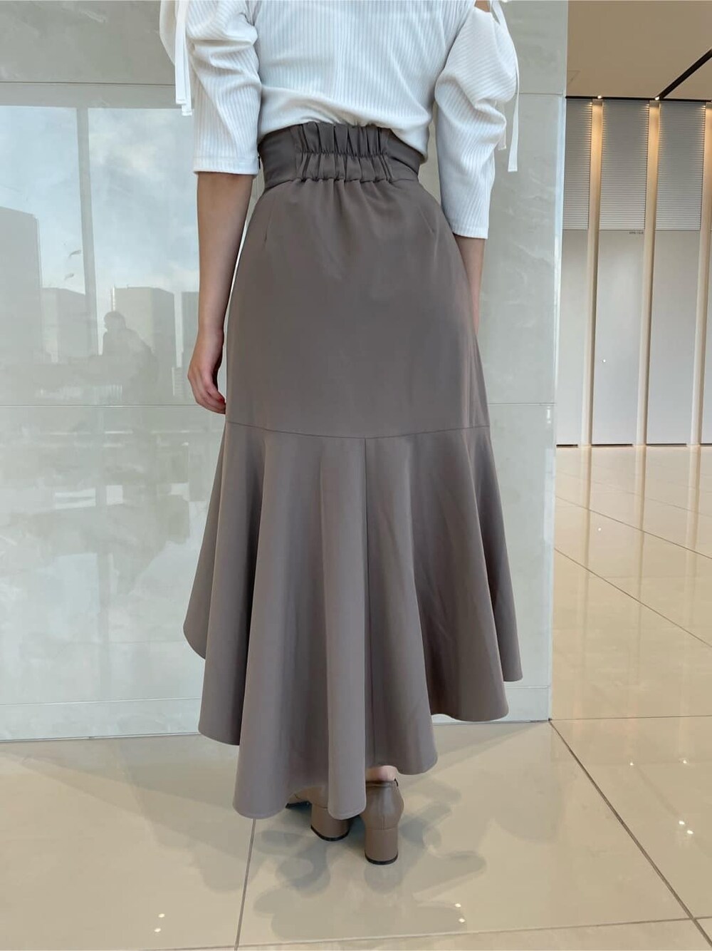 ベージュ系のスカート、ベージュ系のローファー、ホワイト系のTシャツ/カットソーを着用したレディースの夏コーディネートの9枚目の写真