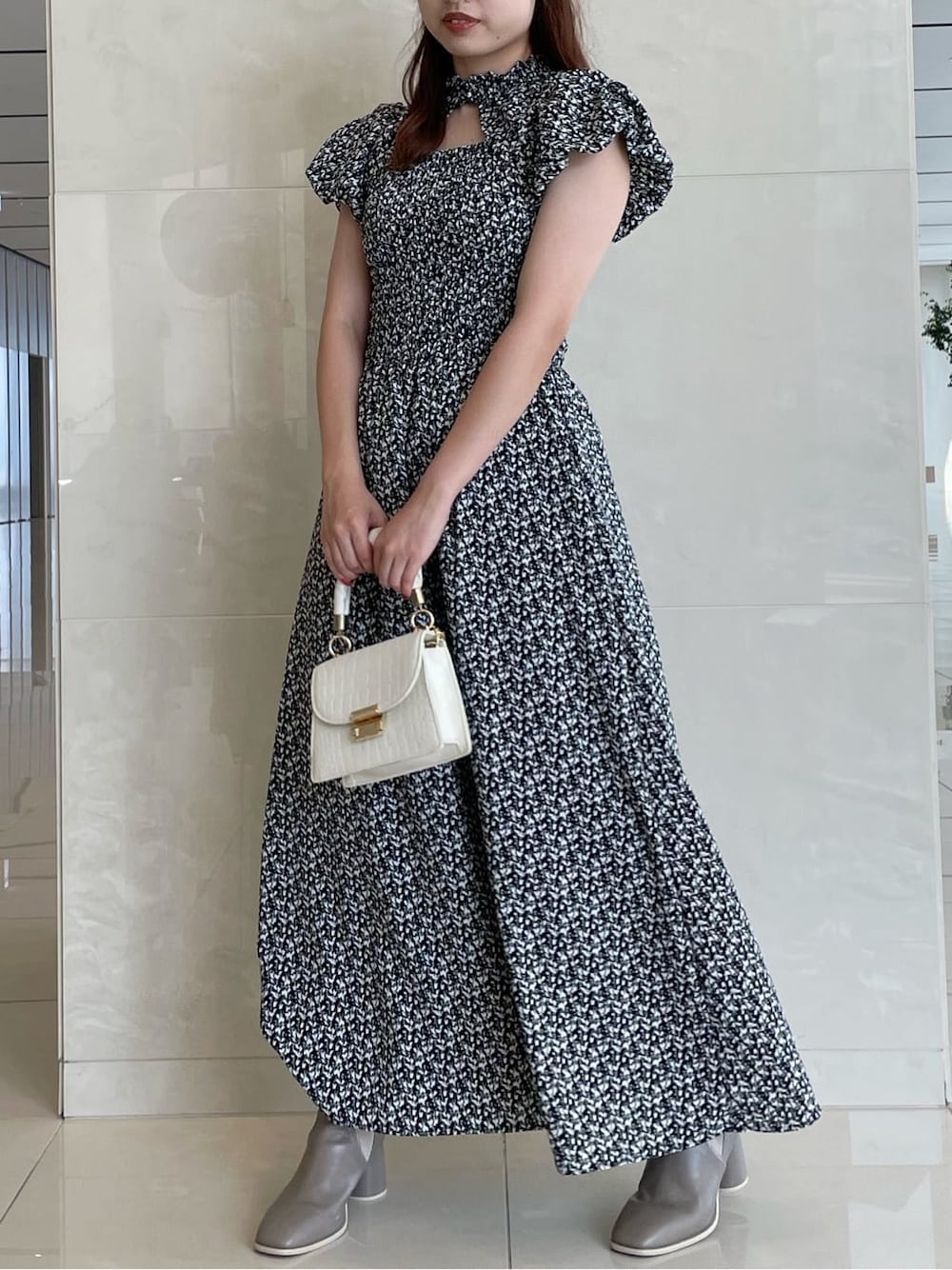 ブラック系のワンピース、ベージュ系のブーツを着用したレディースの夏コーディネートの2枚目の写真