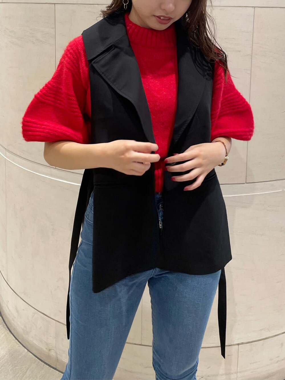 ブラック系のベスト、ブラック系のブーツ、レッド系のニット/セーターを着用したレディースの秋コーディネートの4枚目の写真