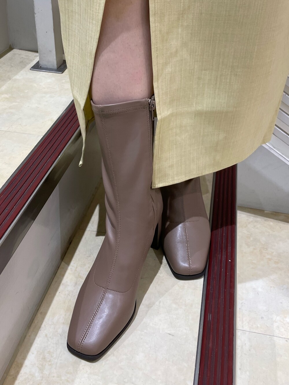 ホワイト系のシャツ/ブラウス、イエロー系のスカート、ベージュ系のブーツを着用したレディースの夏コーディネートの10枚目の写真