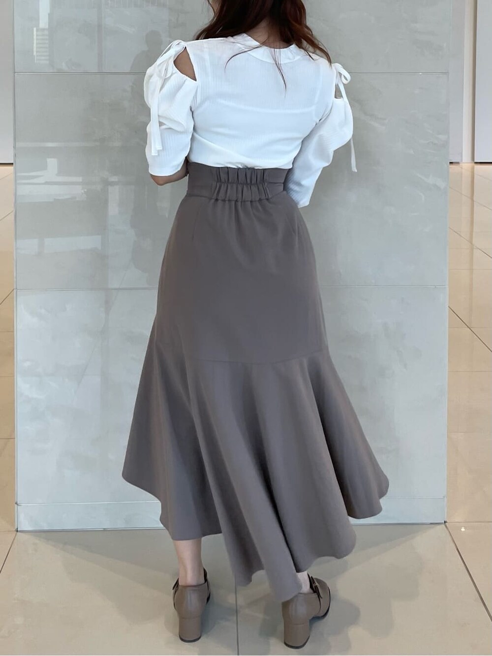 ベージュ系のスカート、ベージュ系のローファー、ホワイト系のTシャツ/カットソーを着用したレディースの夏コーディネートの3枚目の写真