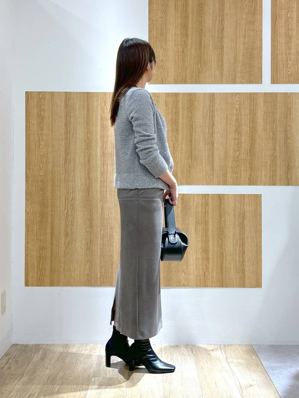 ブラック系のブーツ、ブラック系のショルダーバッグ、グレー系のスカートを着用したレディースの秋コーディネートの3枚目の写真