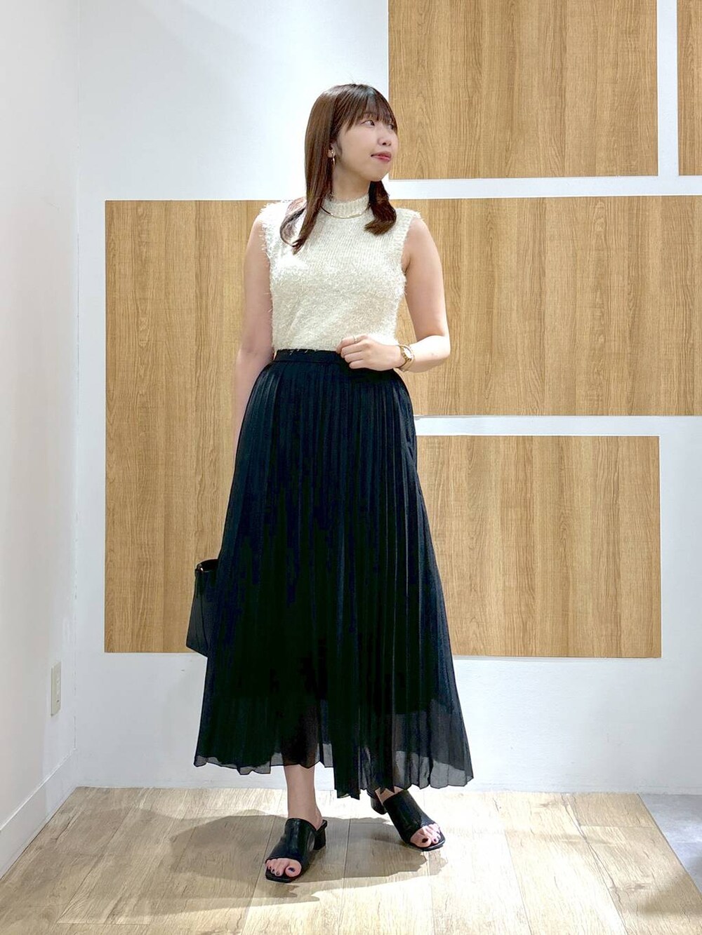 ブラック系のハンドバッグ、ブラック系のスカート、ホワイト系のニット/セーターを着用したレディースの夏コーディネートの5枚目の写真