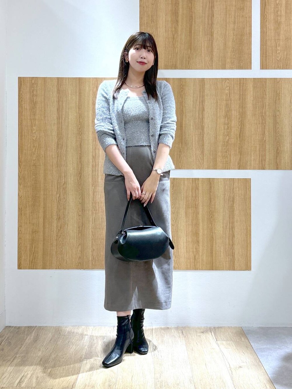 ブラック系のブーツ、ブラック系のショルダーバッグ、グレー系のスカートを着用したレディースの秋コーディネートの5枚目の写真