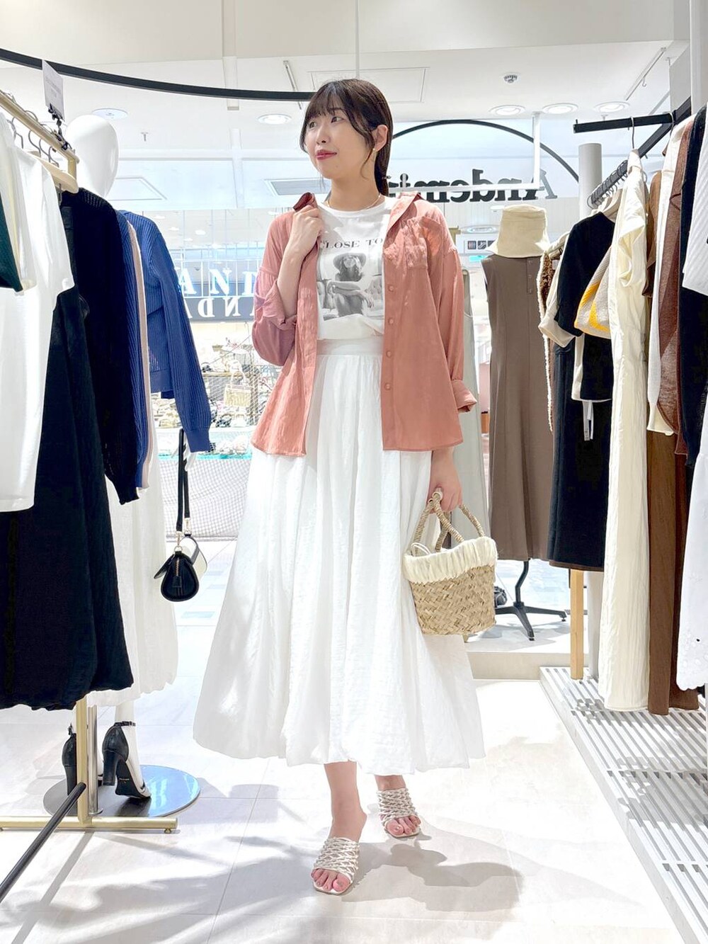 ベージュ系のかごバッグ、ホワイト系のサンダル、ホワイト系のTシャツ/カットソーを着用したレディースの夏コーディネートの3枚目の写真