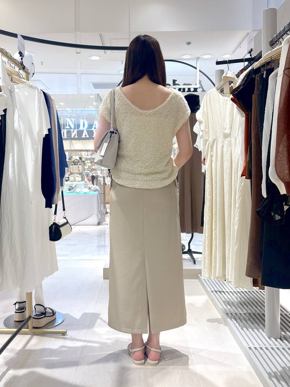 ホワイト系のサンダル、ホワイト系のハンドバッグ、ベージュ系のスカートを着用したレディースの夏コーディネートの4枚目の写真