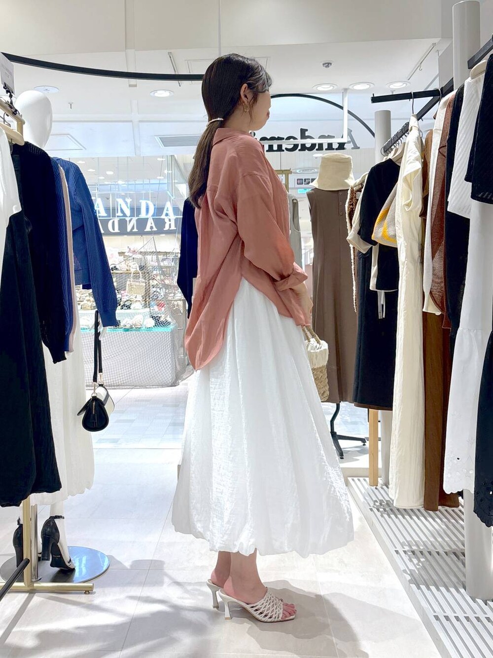 ベージュ系のかごバッグ、ホワイト系のサンダル、ホワイト系のTシャツ/カットソーを着用したレディースの夏コーディネートの4枚目の写真