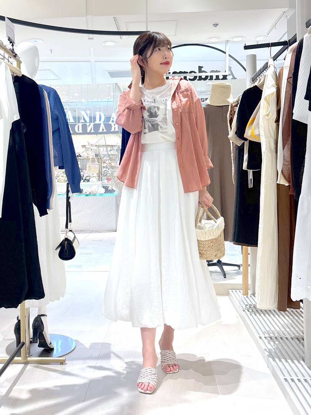 ベージュ系のかごバッグ、ホワイト系のサンダル、ホワイト系のTシャツ/カットソーを着用したレディースの夏コーディネートの2枚目の写真