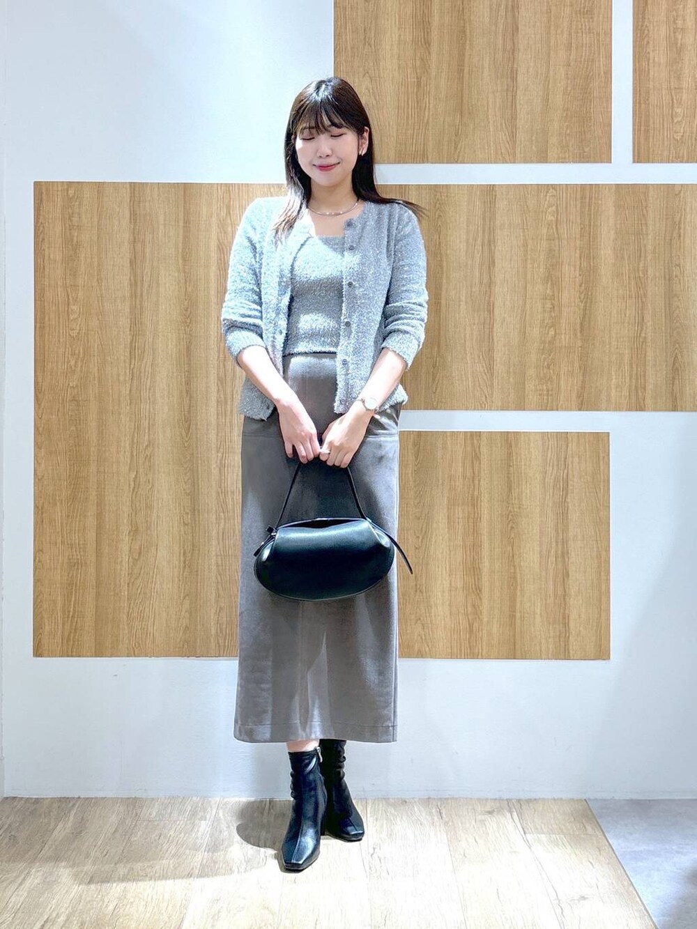 ブラック系のブーツ、ブラック系のショルダーバッグ、グレー系のスカートを着用したレディースの秋コーディネートの2枚目の写真