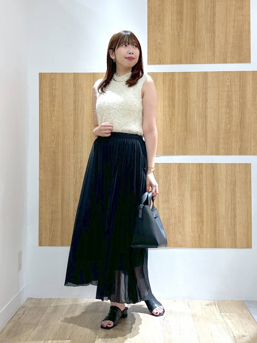 ブラック系のハンドバッグ、ブラック系のスカート、ホワイト系のニット/セーターを着用したレディースの夏コーディネートの2枚目の写真