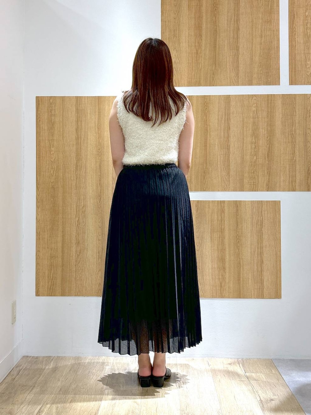 ブラック系のハンドバッグ、ブラック系のスカート、ホワイト系のニット/セーターを着用したレディースの夏コーディネートの4枚目の写真