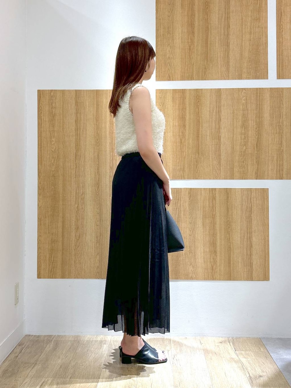 ブラック系のハンドバッグ、ブラック系のスカート、ホワイト系のニット/セーターを着用したレディースの夏コーディネートの3枚目の写真