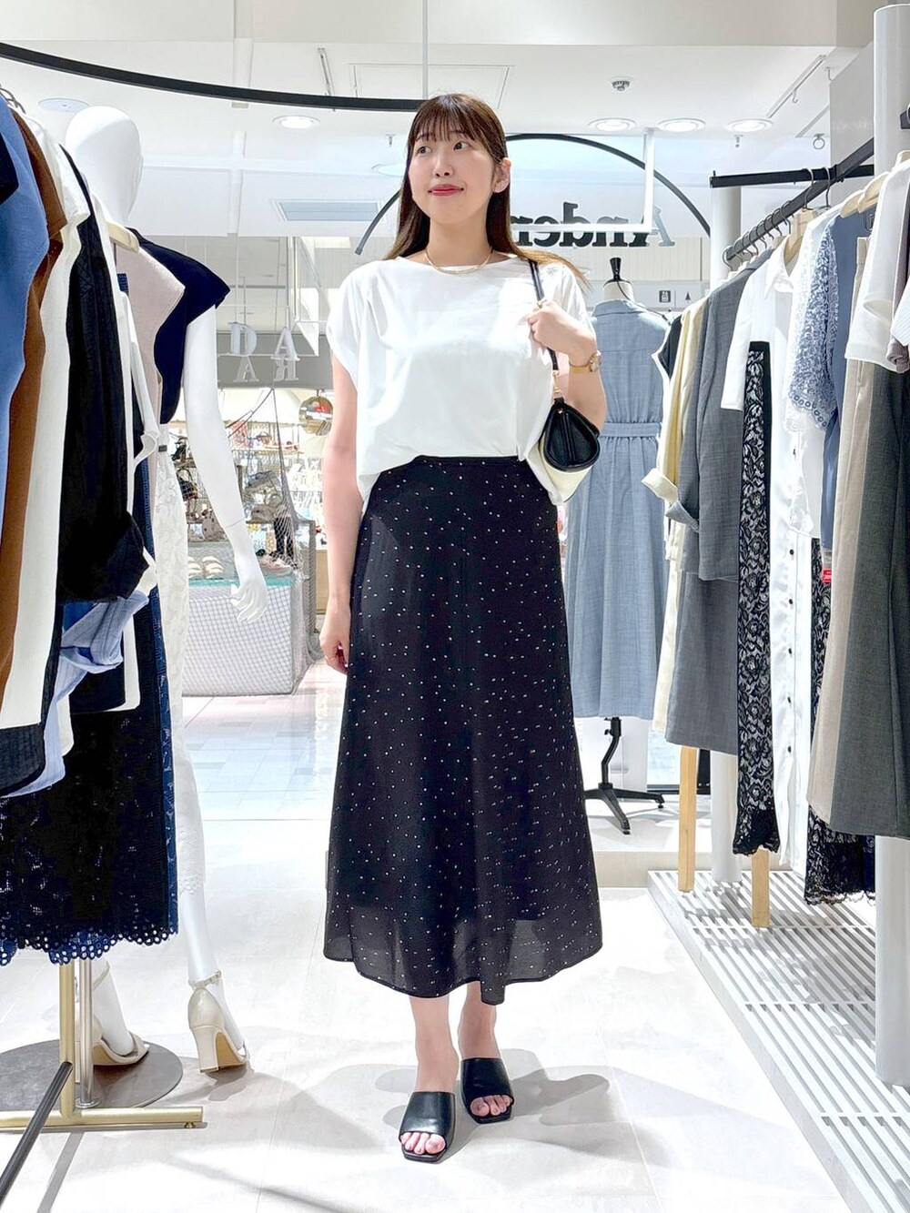 ブラック系のサンダル、ベージュ系のショルダーバッグ、ブラック系のスカートを着用したレディースの夏コーディネートの2枚目の写真