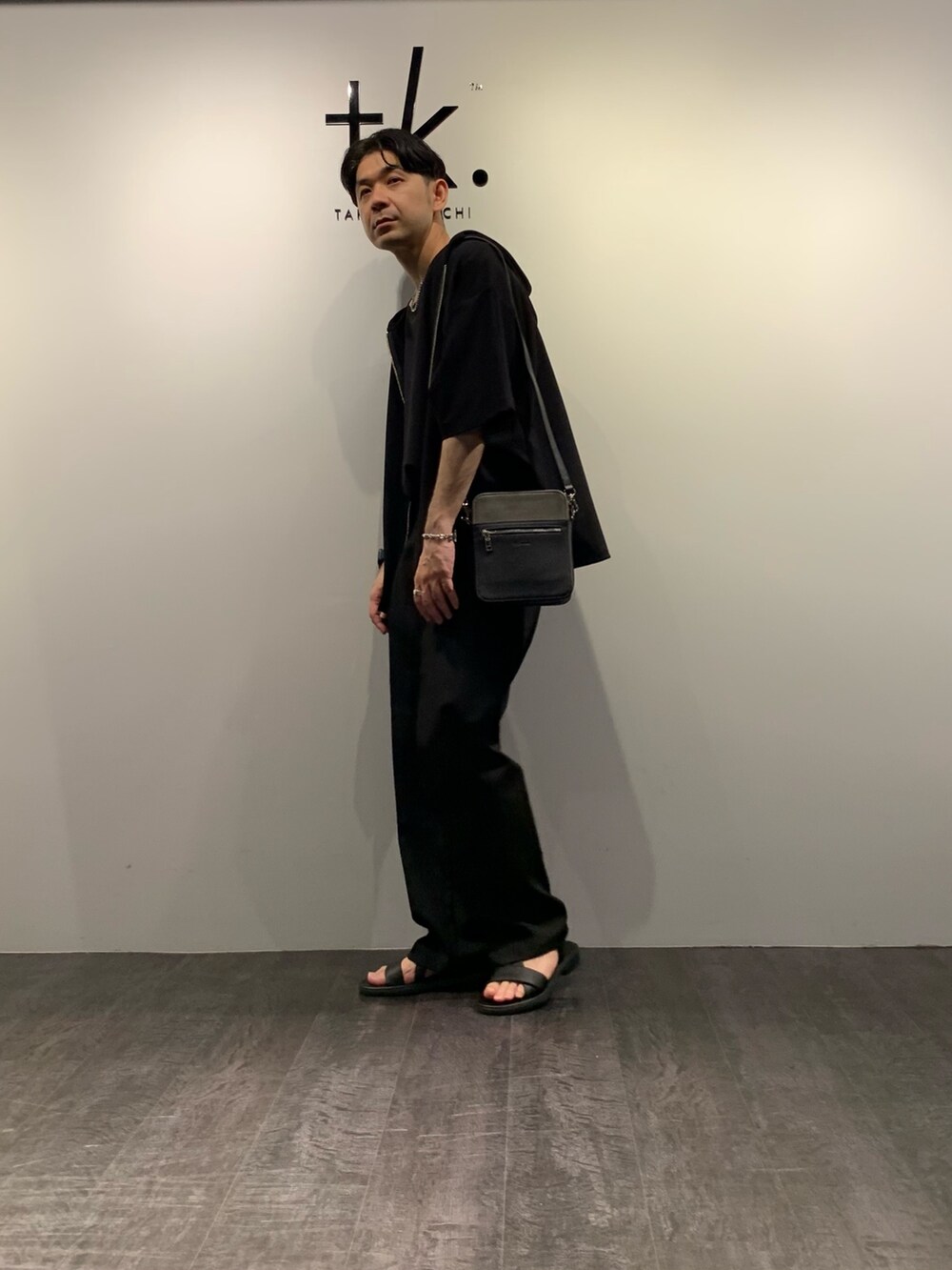 ブラック系のサンダル、ブラック系のスラックス、ブラック系のTシャツ/カットソーを着用したメンズの夏コーディネートの2枚目の写真