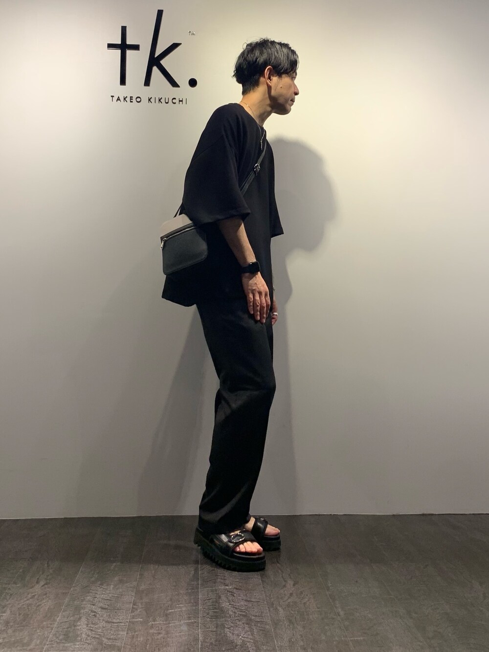 ブラック系のTシャツ/カットソー、ブラック系のサンダル、ブラック系のスラックスを着用したメンズの夏コーディネートの2枚目の写真