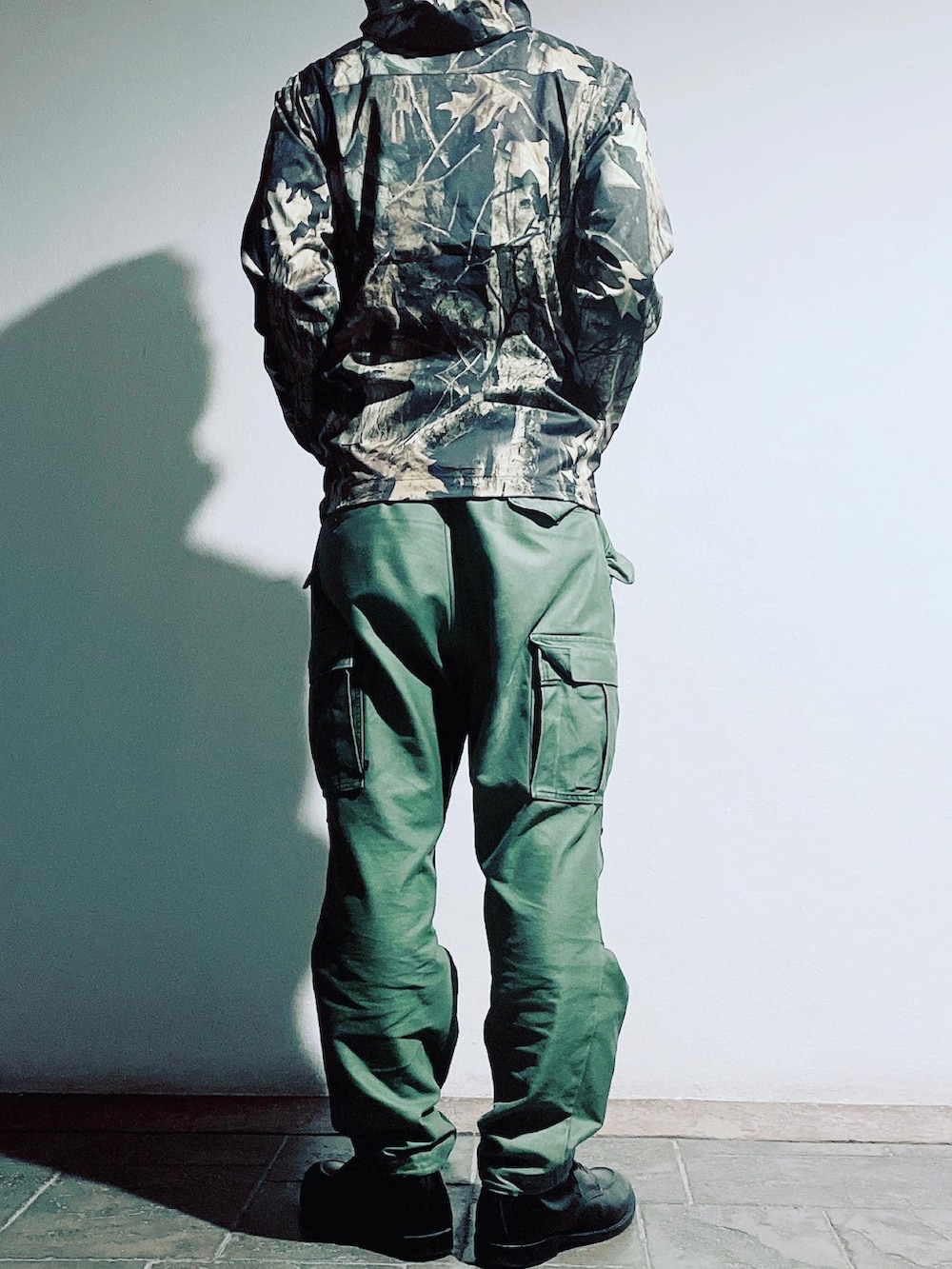 グリーン系のカーゴパンツ、ブラック系のブーツ、ブラウン系のナイロンジャケットを着用したメンズの秋コーディネートの3枚目の写真