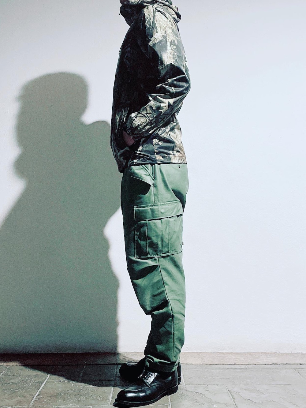 グリーン系のカーゴパンツ、ブラック系のブーツ、ブラウン系のナイロンジャケットを着用したメンズの秋コーディネートの2枚目の写真