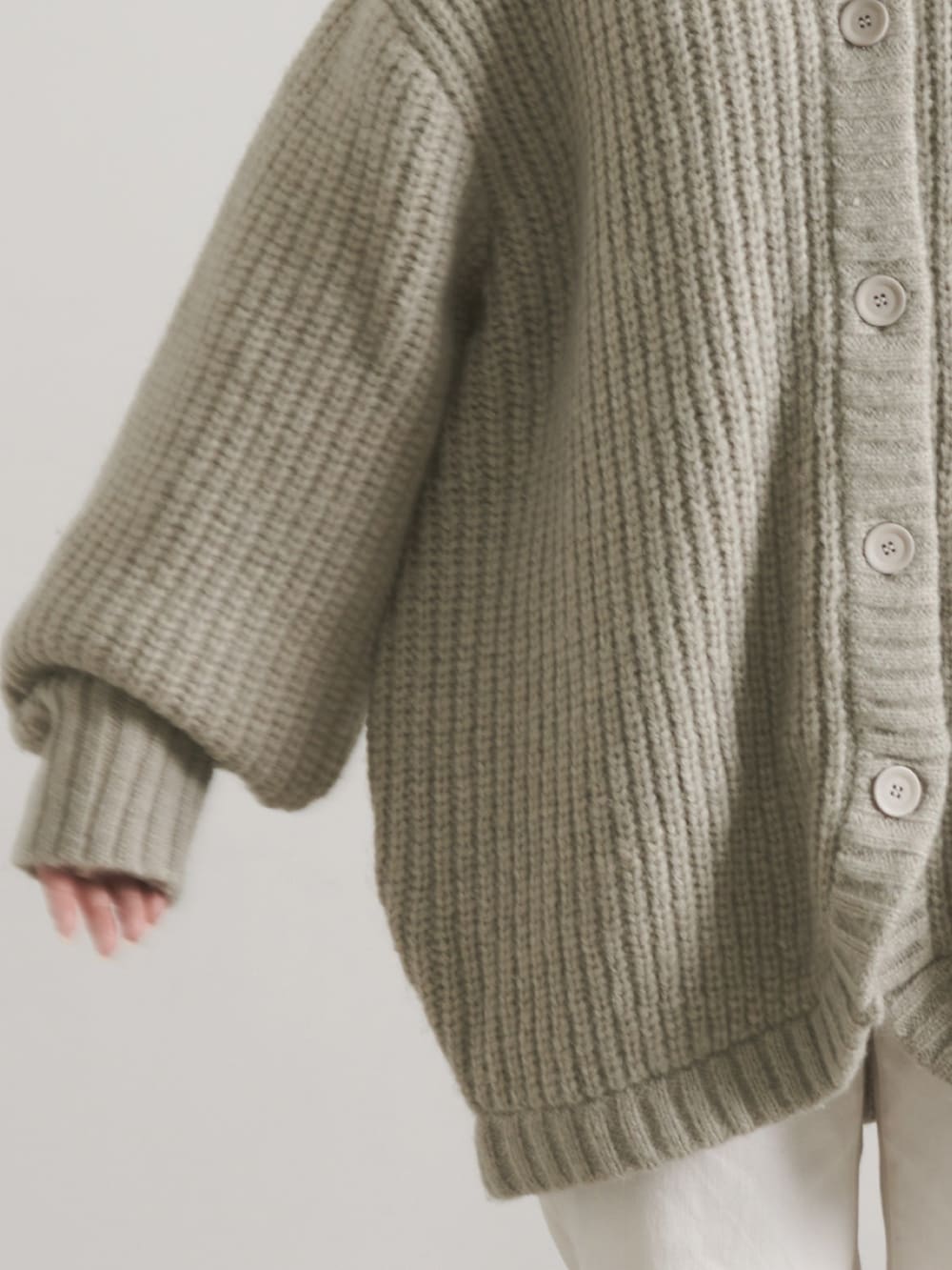 グリーン系のスニーカー、ブラック系のスカート、ホワイト系のカーディガン/ボレロを着用したレディースの秋コーディネートの3枚目の写真