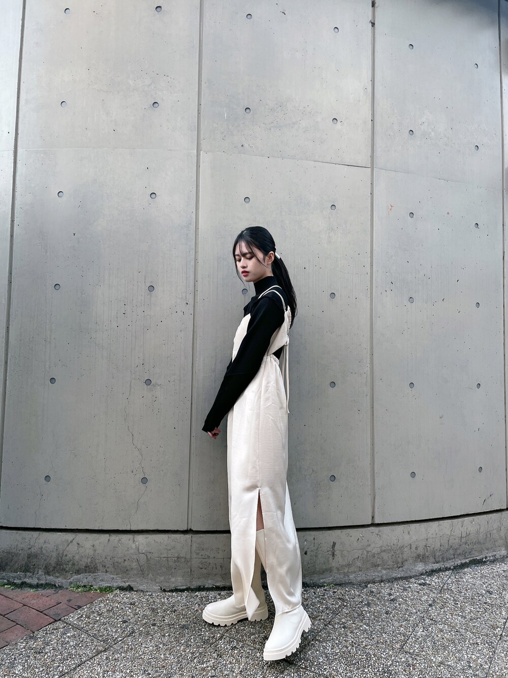 ベージュ系のワンピース、ホワイト系のブーツ、ブラック系のニット/セーターを着用したレディースの冬コーディネートの2枚目の写真