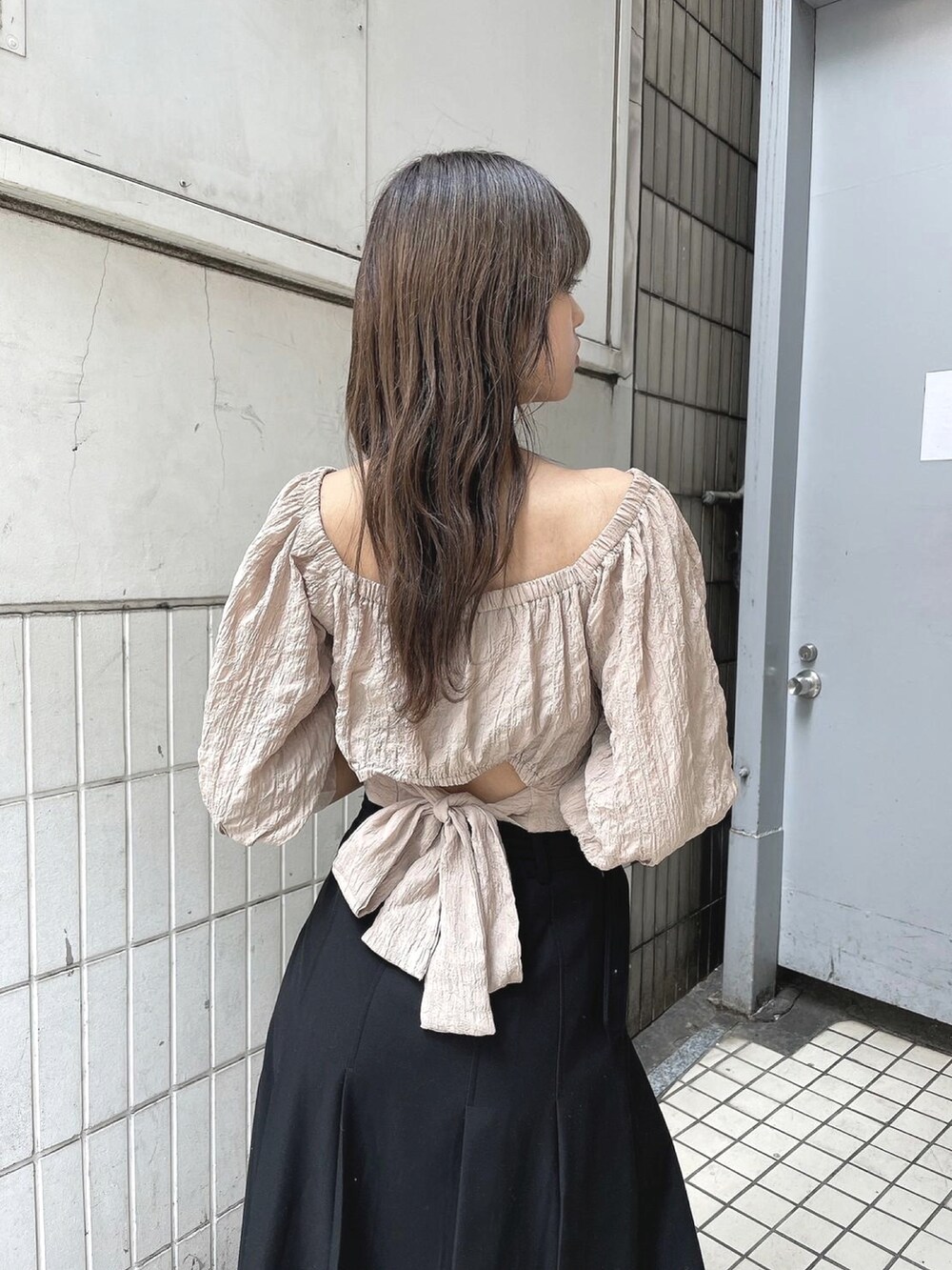 ブラック系のスカート、ベージュ系のTシャツ/カットソーを着用したレディースの春コーディネートの2枚目の写真