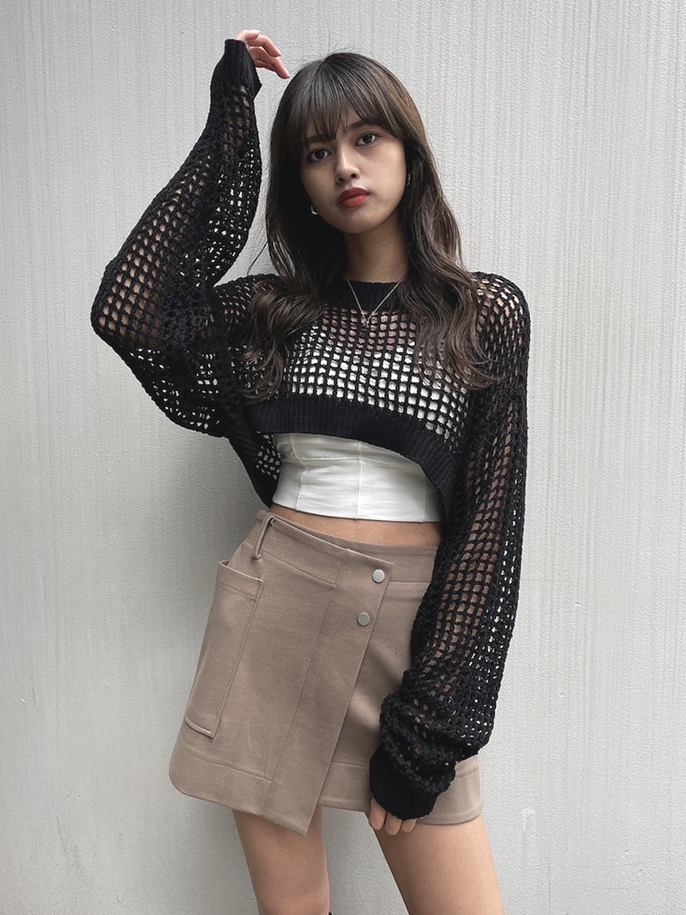 ブラック系のニット/セーター、ベージュ系のスカートを着用したレディースの春コーディネートの3枚目の写真